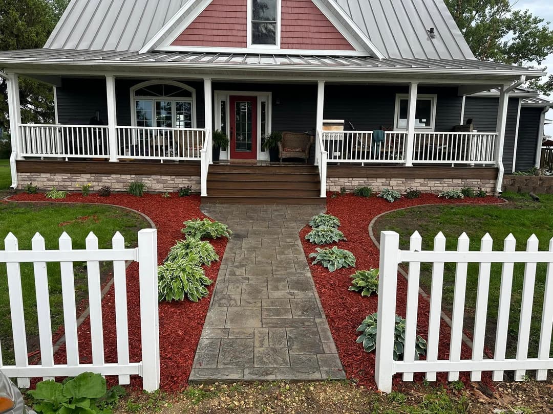 Charming home exterior with a landscaped garden, stone walkway, and white picket fence.