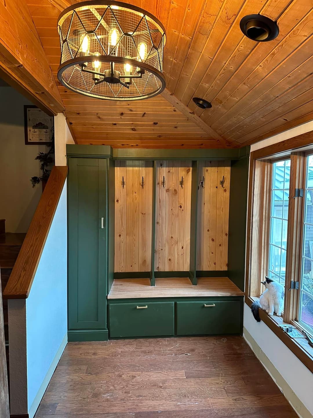 Entryway mudroom with wooden hooks, bench, and storage in a cozy, rustic design.