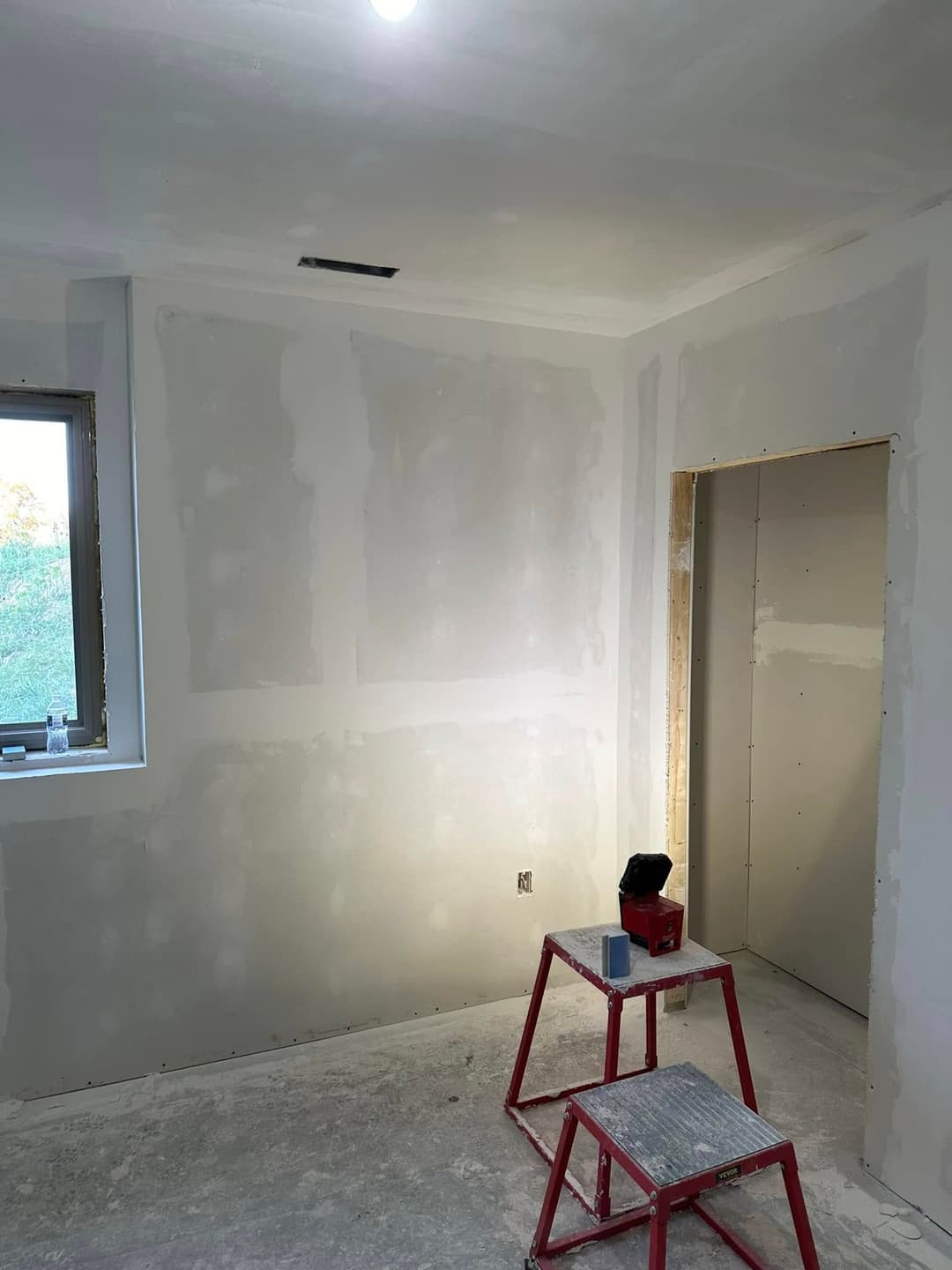 Unfinished room with drywall, a ladder, and a workbench awaiting final construction touches.