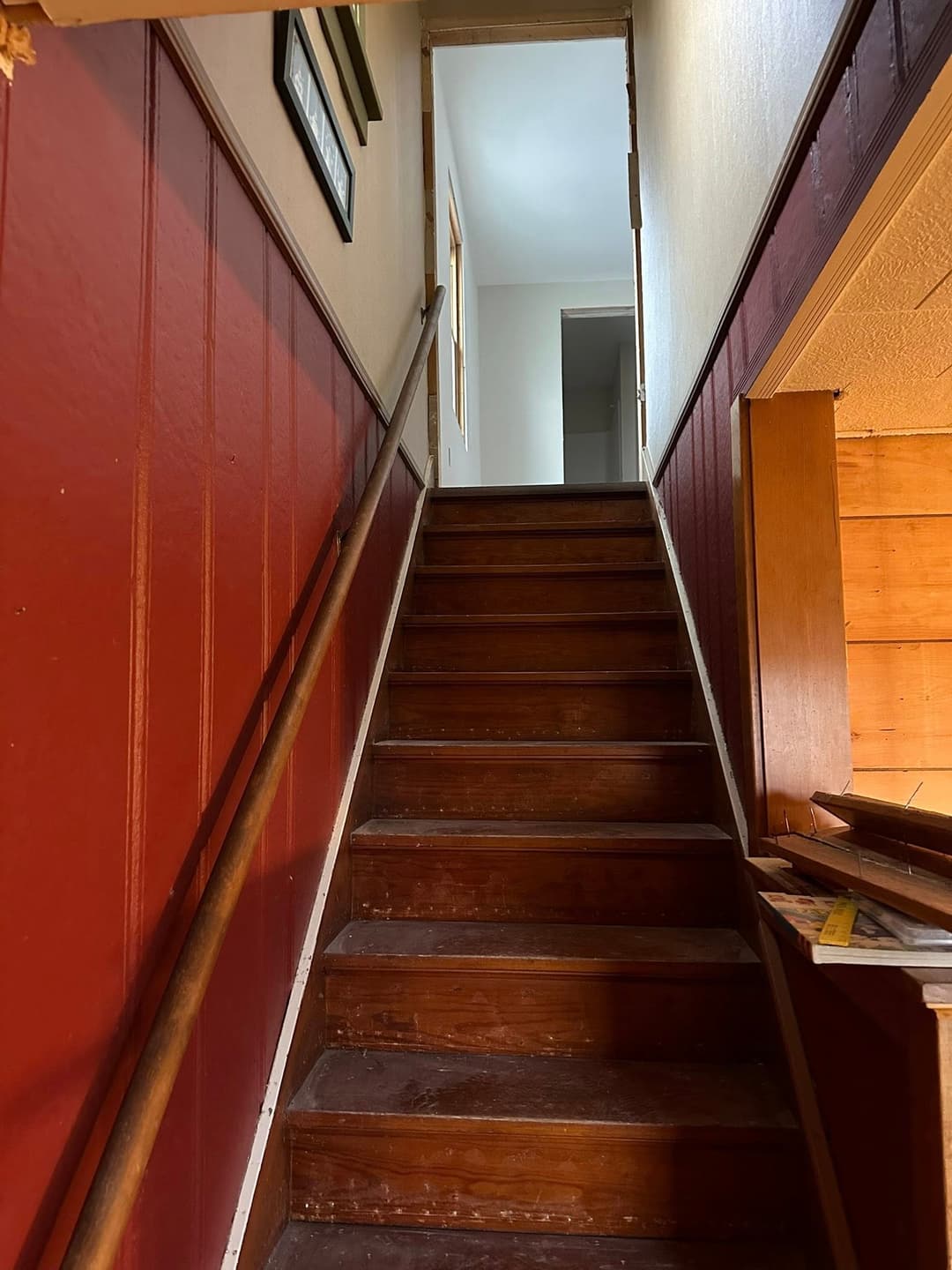 Wooden staircase leading to a light-filled hallway in a cozy home interior.