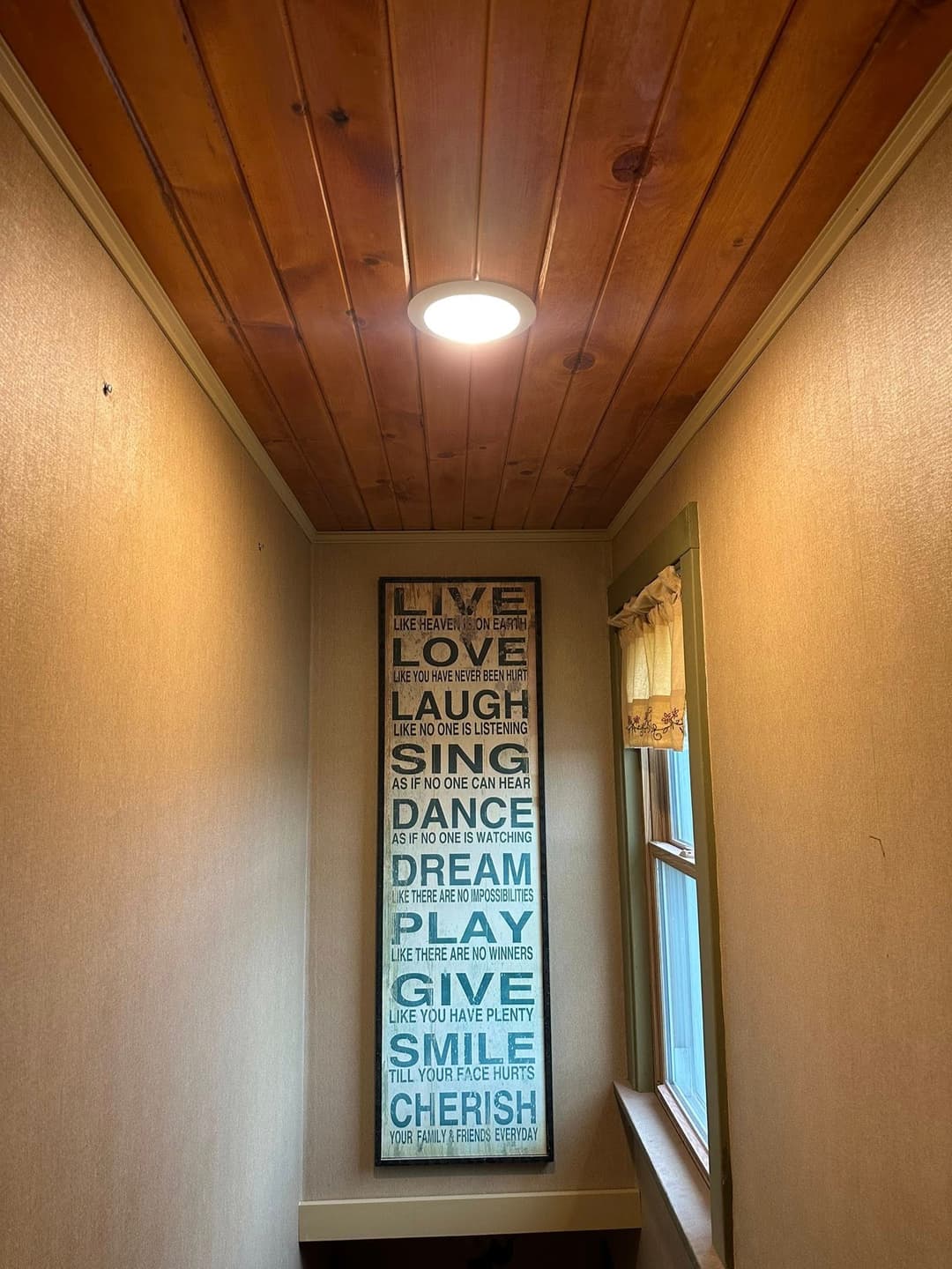 Bright hallway featuring inspirational wall art and warm wooden ceiling.