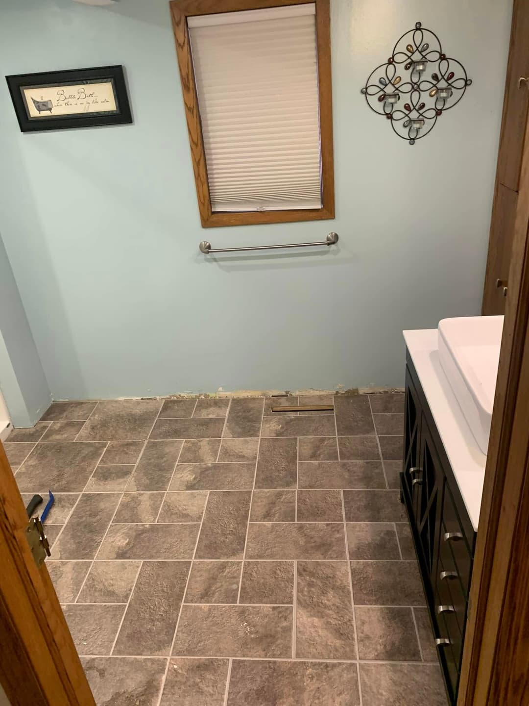 Renovated bathroom with gray tile floor, light blue walls, and modern sink vanity.