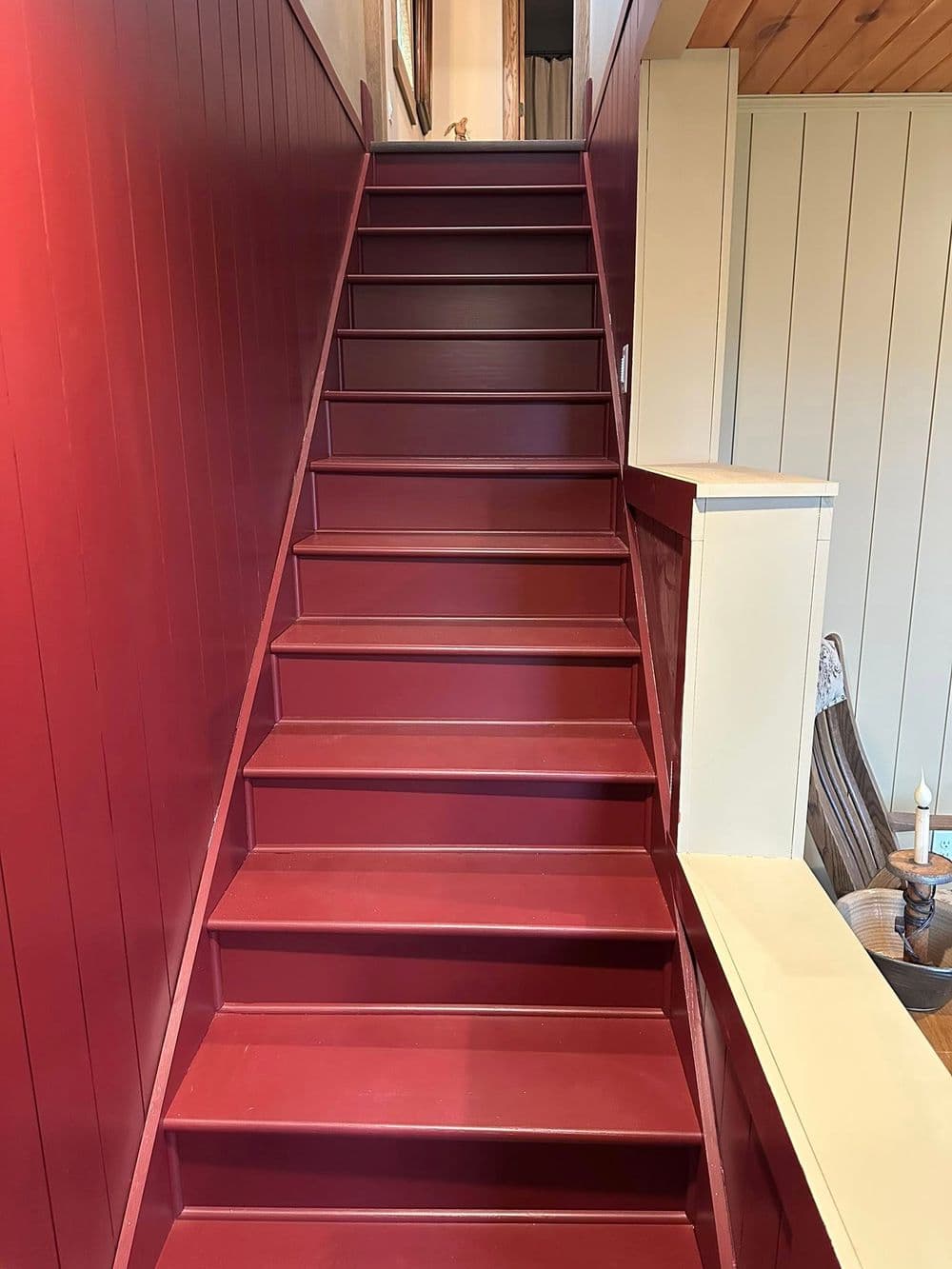 Staircase with deep red walls and wooden accents leading to an upper level.